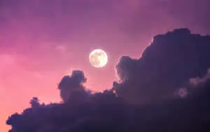 a moon is seen through a purple cloudy sky