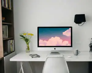 a white desk with a computer and a vase