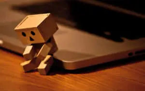 a small cardboard figure sitting on top of a laptop