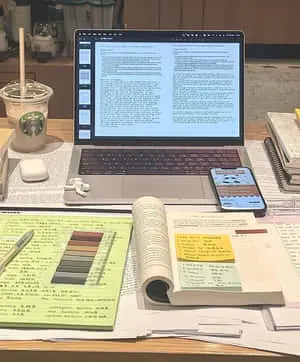 a desk with a laptop, notebook, and other items