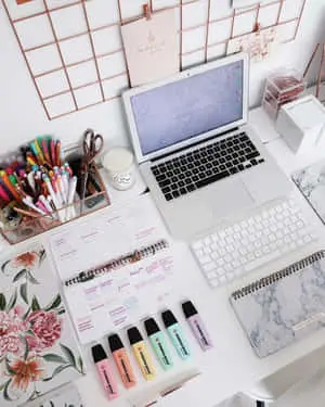 a desk with a laptop, pens, and other items
