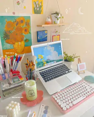 a desk with a laptop, keyboard, and a vase