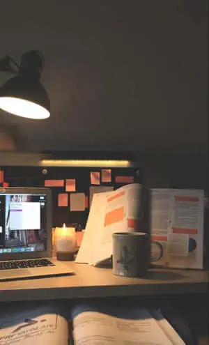 a desk with a laptop, books, and a lamp