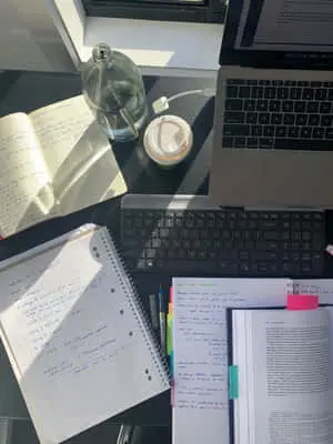 a desk with a laptop, notebook, and a pen