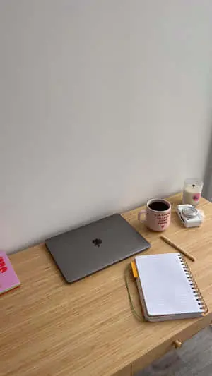 a wooden desk with a laptop and a notebook